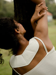 woman wearing neckheat stretching against a tree